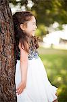 Portrait of girl leaning against tree trunk, smiling