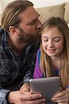 Girl looking at digital tablet with father