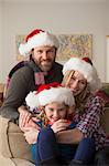 Parents and child in Santa hat posing for camera