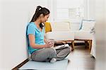 Woman sitting on mat using digital tablet