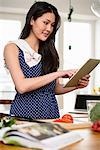 Woman with tea towel over shoulder using digital tablet