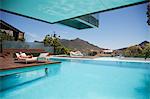 Woman sunbathing on lounge chair at poolside with mountain view