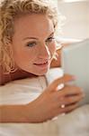 Close up of woman laying in bed using digital tablet