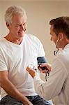 Doctor checking senior man's blood pressure in doctor's office