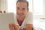 Portrait of smiling man using digital tablet in bed