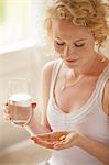 Woman holding glass of water and pills