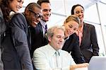 Smiling business people sharing laptop in meeting