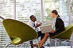 Businessman and businesswoman with laptop talking in lobby