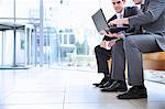 Businessmen sharing laptop in lobby