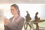 Smiling businesswoman text messaging with cell phone