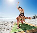 Woman piggybacking enthusiastic man on beach