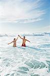 Couple standing in ocean with arms raised