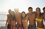 Portrait of friends in bikinis and swim trunks on beach