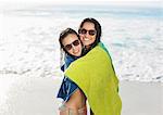 Portrait of smiling friends wrapped in towel on beach