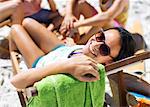 Portrait of happy woman sitting in lounge chair on beach