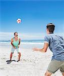 Man heading soccer ball on beach