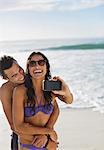Happy couple taking self-portrait with camera phone on beach