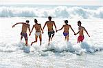 Friends holding hands and splashing in ocean