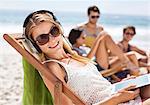 Portrait of happy woman listening to headphones at beach