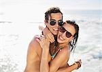 Portrait of enthusiastic couple in sunglasses hugging on beach