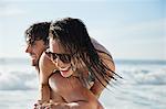 Man carrying enthusiastic woman on beach