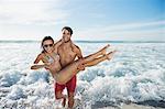 Enthusiastic man carrying woman on beach