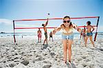 Portrait of confident woman gesturing thumbs up on beach volleyball court