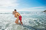 Enthusiastic couple hugging and splashing in ocean