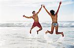 Couple jumping with arms raised on beach
