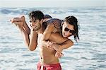 Happy man carrying woman on beach