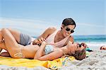 Happy couple laying on blanket at beach