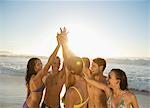 Friends high fiving in huddle at beach