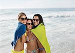 Portrait of smiling friends wrapped in towel at beach