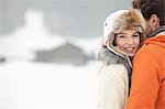 Portrait of smiling woman hugging man in snowy field