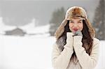 Portrait of smiling woman wearing fur hat and gloves in snowy field