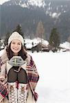 Portrait of smiling woman drinking coffee in snowy field