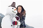 Portrait of happy woman hugging snowman