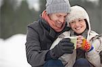 Happy couple drinking coffee in snow