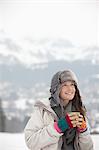 Smiling woman drinking coffee in snowy field