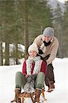 Happy couple sledding in snowy woods