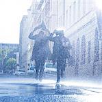 Businessmen covering heads with newspaper in rain