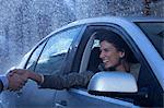 Smiling businesswoman in car extending handshake in rain