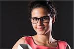 Close-up portrait of teenage girl wearing horn-rimmed eyeglasses, holding binder, smiling and looking at camera