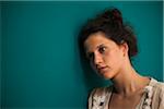 Portrait of teenaged girl, leaning against wall, looking off into the distance