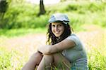 Portrait of teenaged girl sitting in field, smiling and looking at camera, Germany