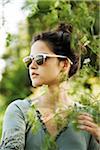 Portrait of teenaged girl outdoors in nature wearing sunglasses, looking into the distance, Germany