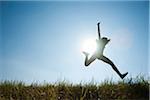 Silhouette of teenaged girl jumping in air across field, Germany