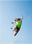 Teenaged girl jumping in mid-air against blue sky, Germany