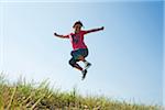 Girl jumping in mid-air over field, Germany