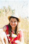 Portrait of Girl wearing hat, sitting in field and smiling at camera, Germany